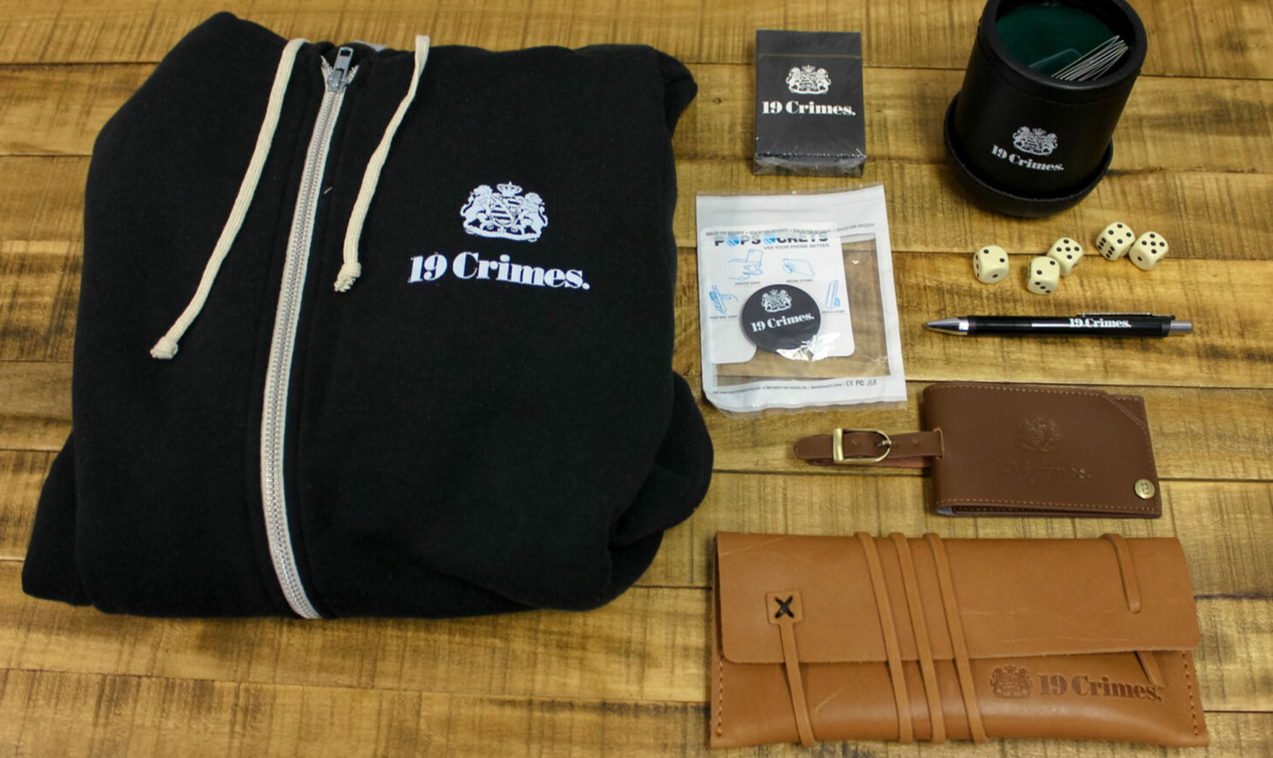 Image of sweatshirt, leather pouch and popsocket with 19 Crimes logo on it.