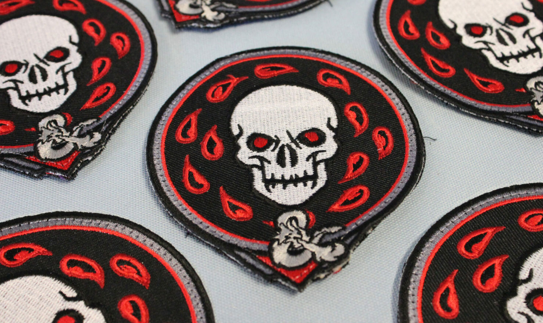 Image of black and red embroidered patch with white skull icon on it