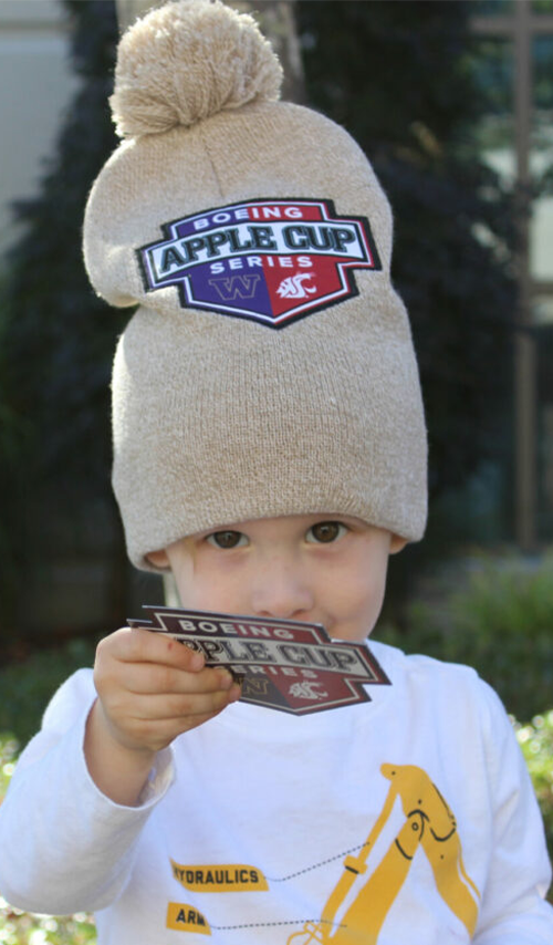 Image of small child wearing a beanie with the Boeing Apple Cup logo on it.