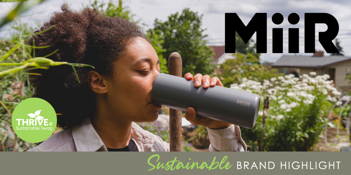 Image of woman standing in a garden drinking out of a black Miir tumbler.