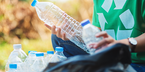 Image of a person holding empty plastic bottles and recycling them.