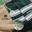Image of various items with the 19 Crimes logo on them. Items include a green and white scarf, jute drawstring bag, necklace with green clovers and a coaster.