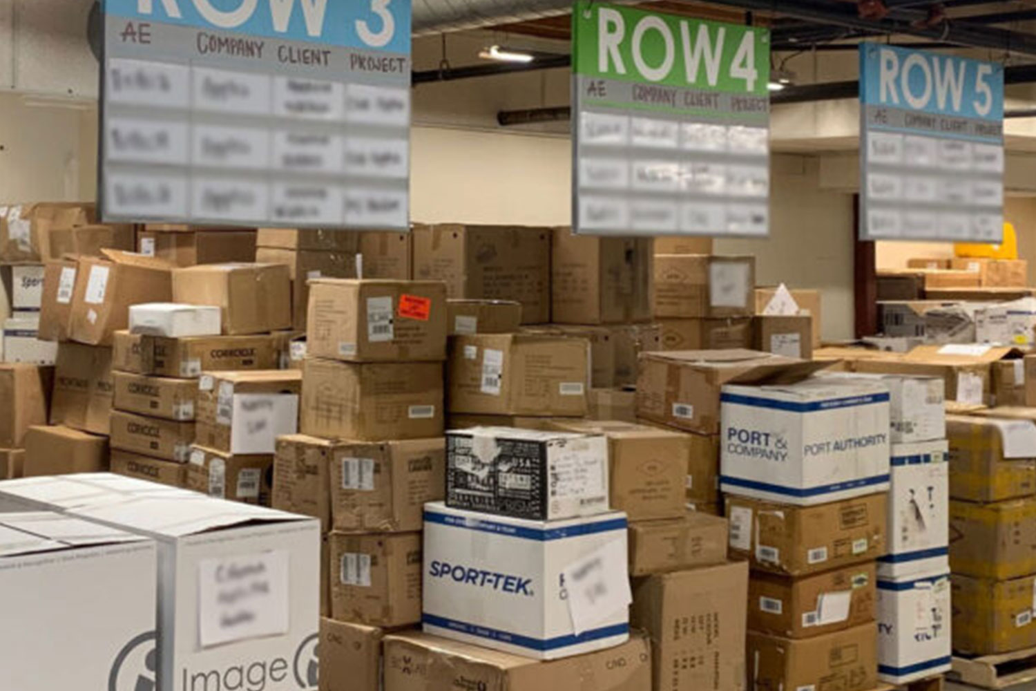 Image of the inside of a warehouse with three rows of pallets full of boxes.