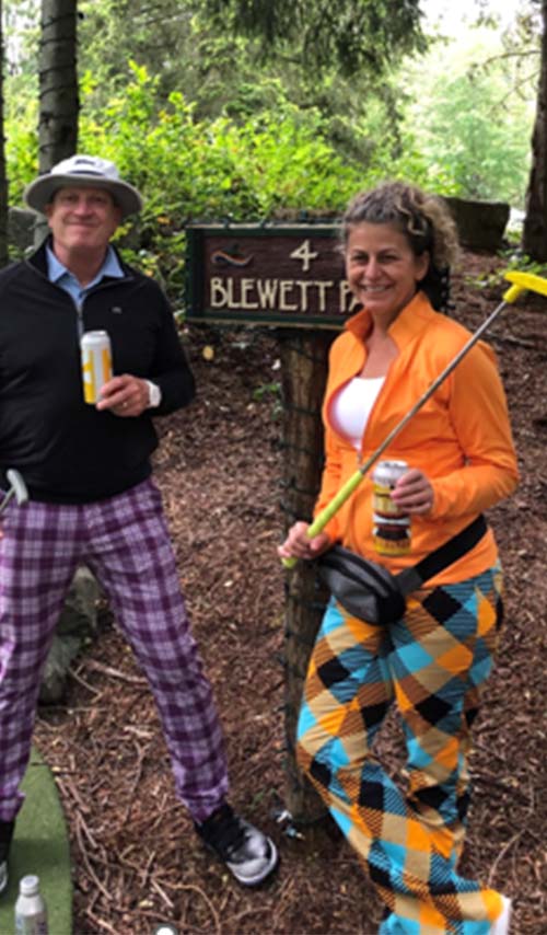 Man and woman dresses in retro golf gear playing putt putt golf