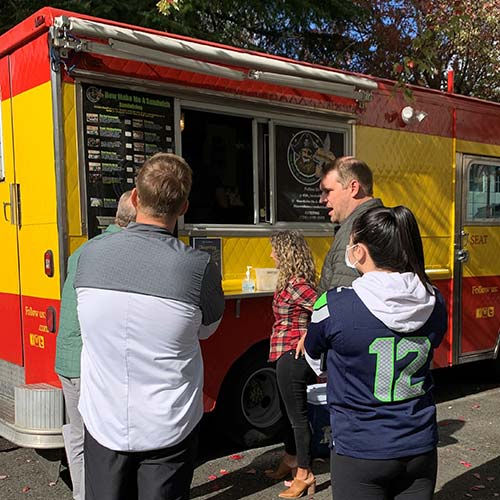 Three people standing in line at a taco truck,