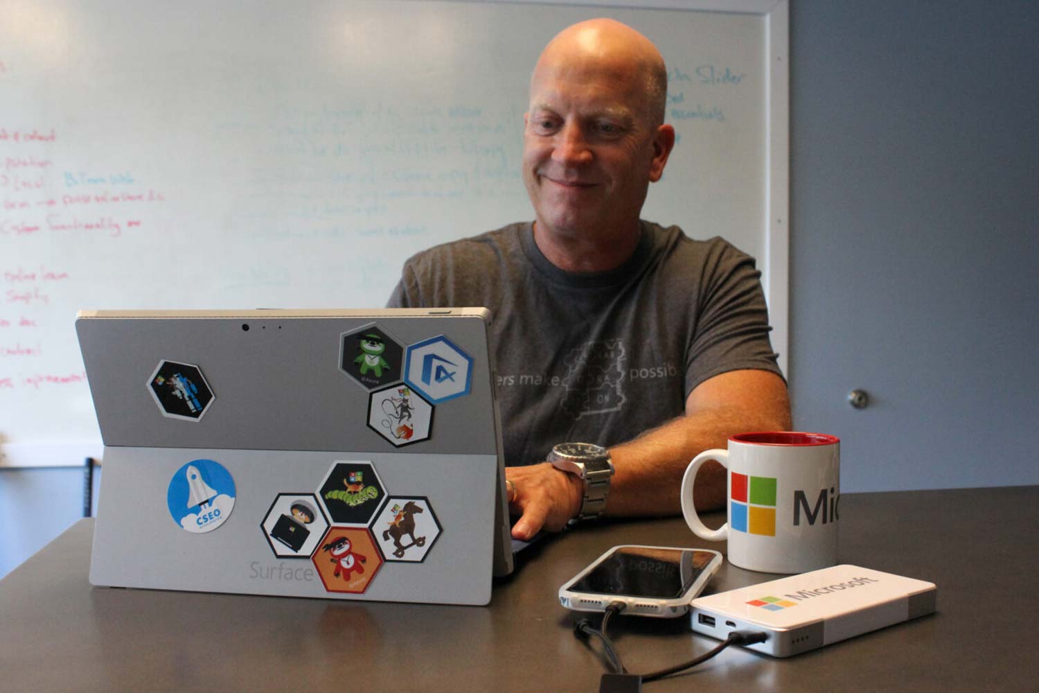 Image of man on tablet sitting at a desk full of tech swag.