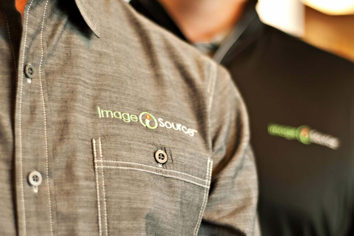 Close up image of man wearing gray button shirt with Image Source logo embroidered on the left chest.