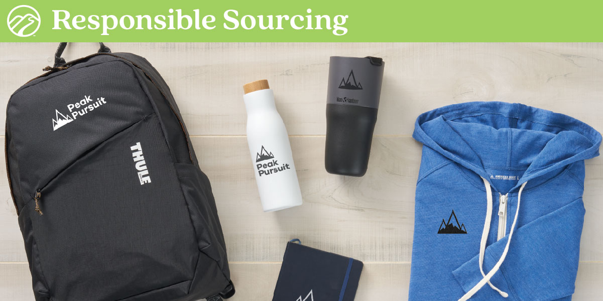 Backpack, water bottle, tumbler and folded hoodie on table.