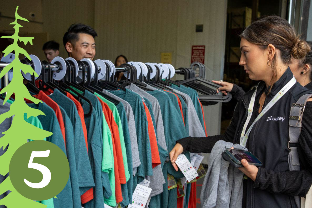 Lady looking at t-shirts on an apparel rack.