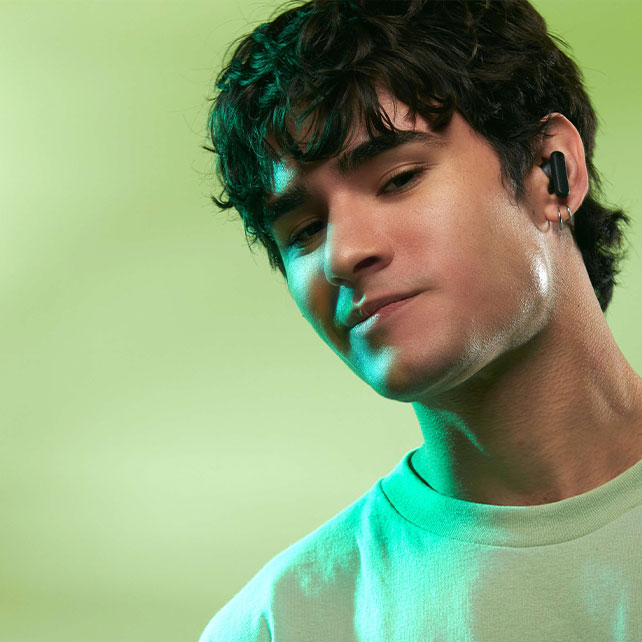 Young man wearing a white t-shirt listening to music with bluetooth headphones.