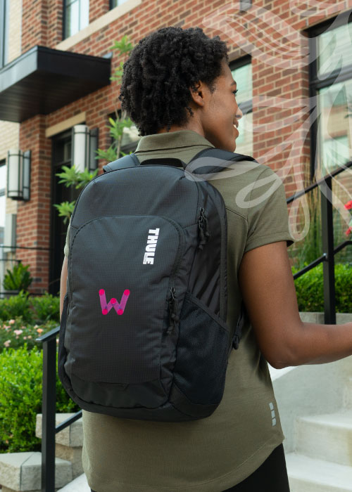 Woman wearing a black backpack walking into a building.