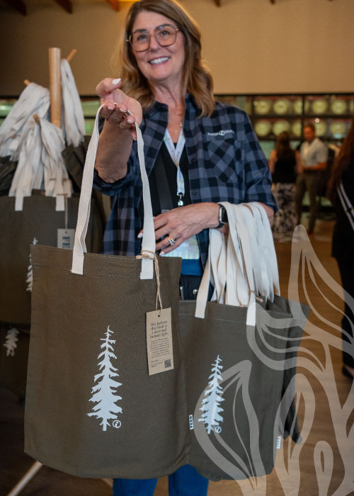 woman handing out reusable tote bags.